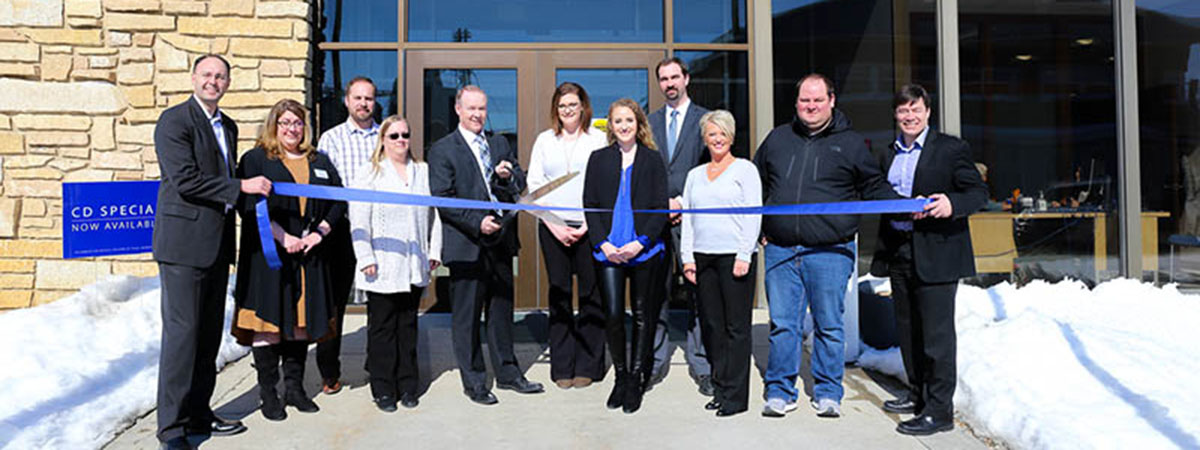 bank employees cut a blue ribbon in front of renovated 
