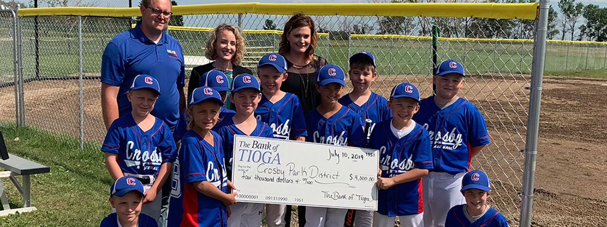 employees and baseball players pose with large donation