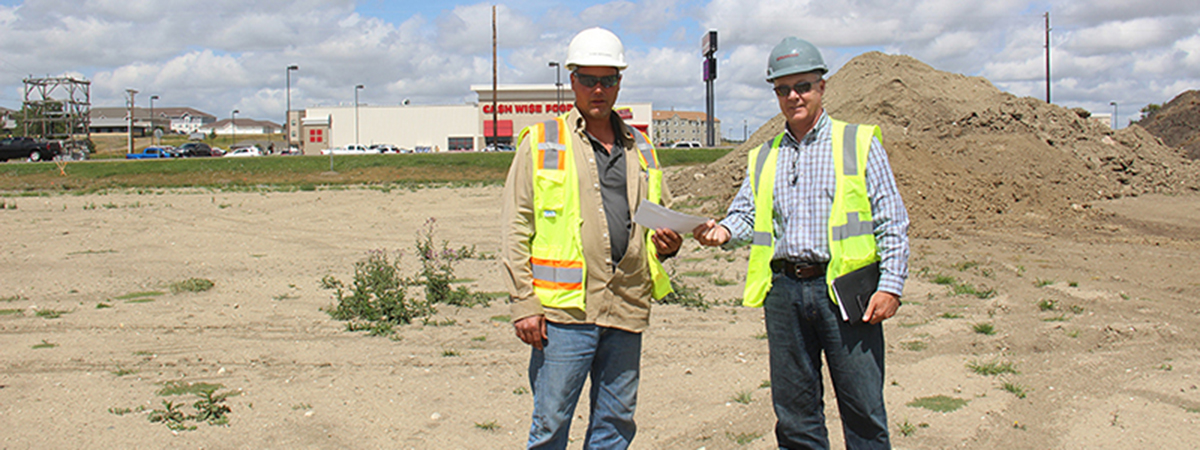 men in construction gear exchange a check at a worksite