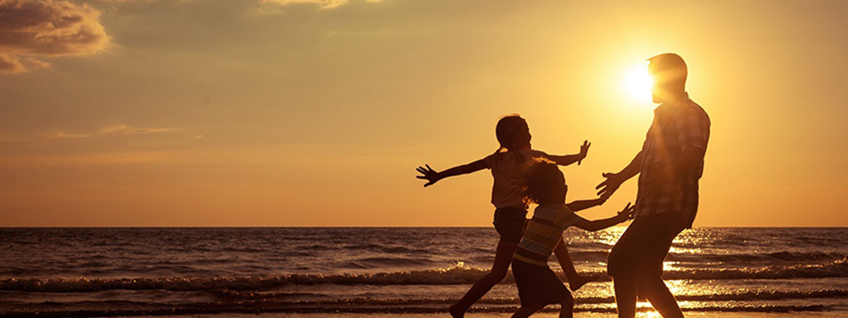 a dad and kids dancing at sunset on the beach