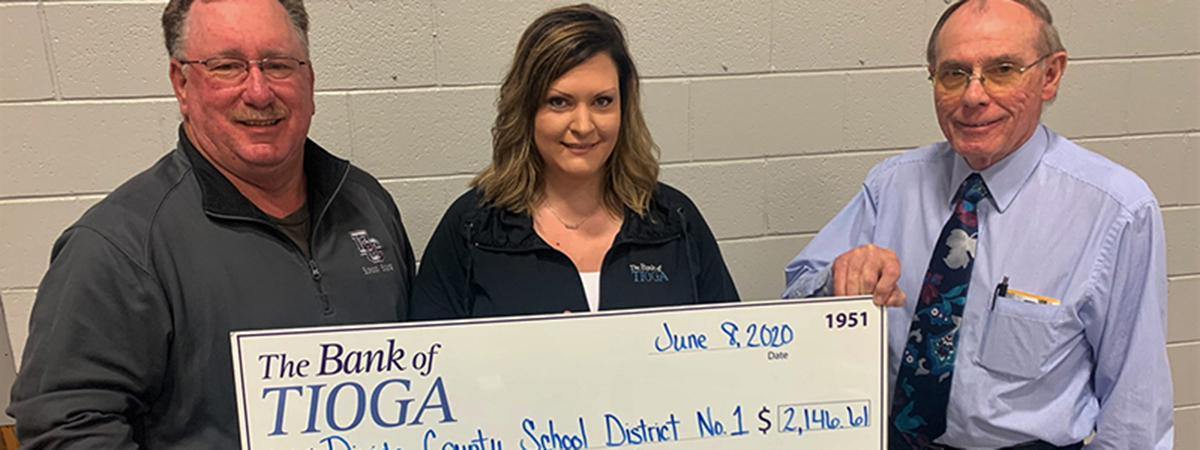 employee and school employees pose with large check